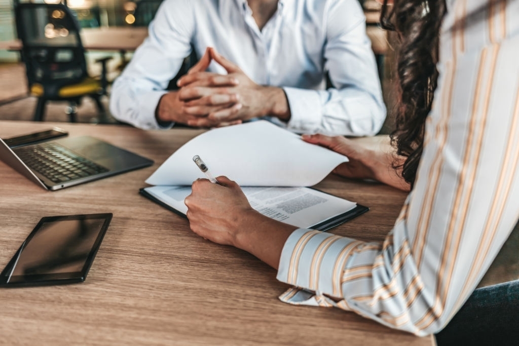 Woman Signing Contract at Table With Businessman Woman Signing Contract at Table With Businessman