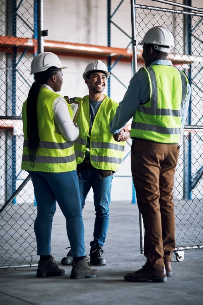 Diverse Group Of Business People In PPE Shaking Hands In Warehouse Diverse Group Of Business People In PPE Shaking Hands In Warehouse