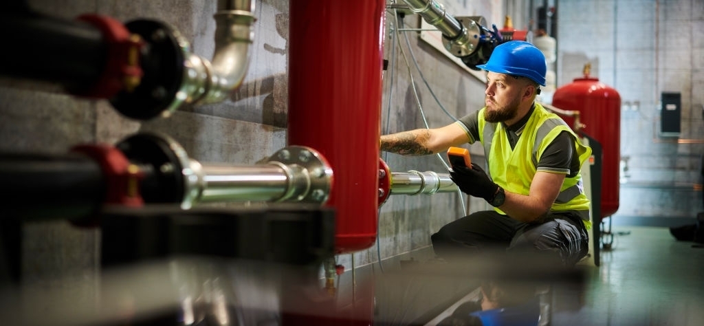 Mechanical Worker Working on Large Red Pipe