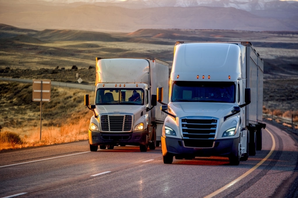 Two 18 Wheelers Driving Side By Side On Highway Two 18 Wheelers Driving Side By Side On Highway