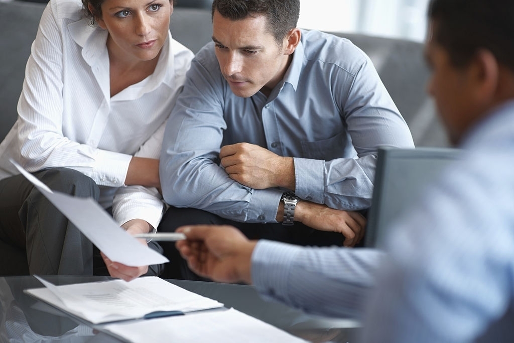 Business People Meet Around Coffee Table Discussing Papers Business People Meet Around Coffee Table Discussing Papers