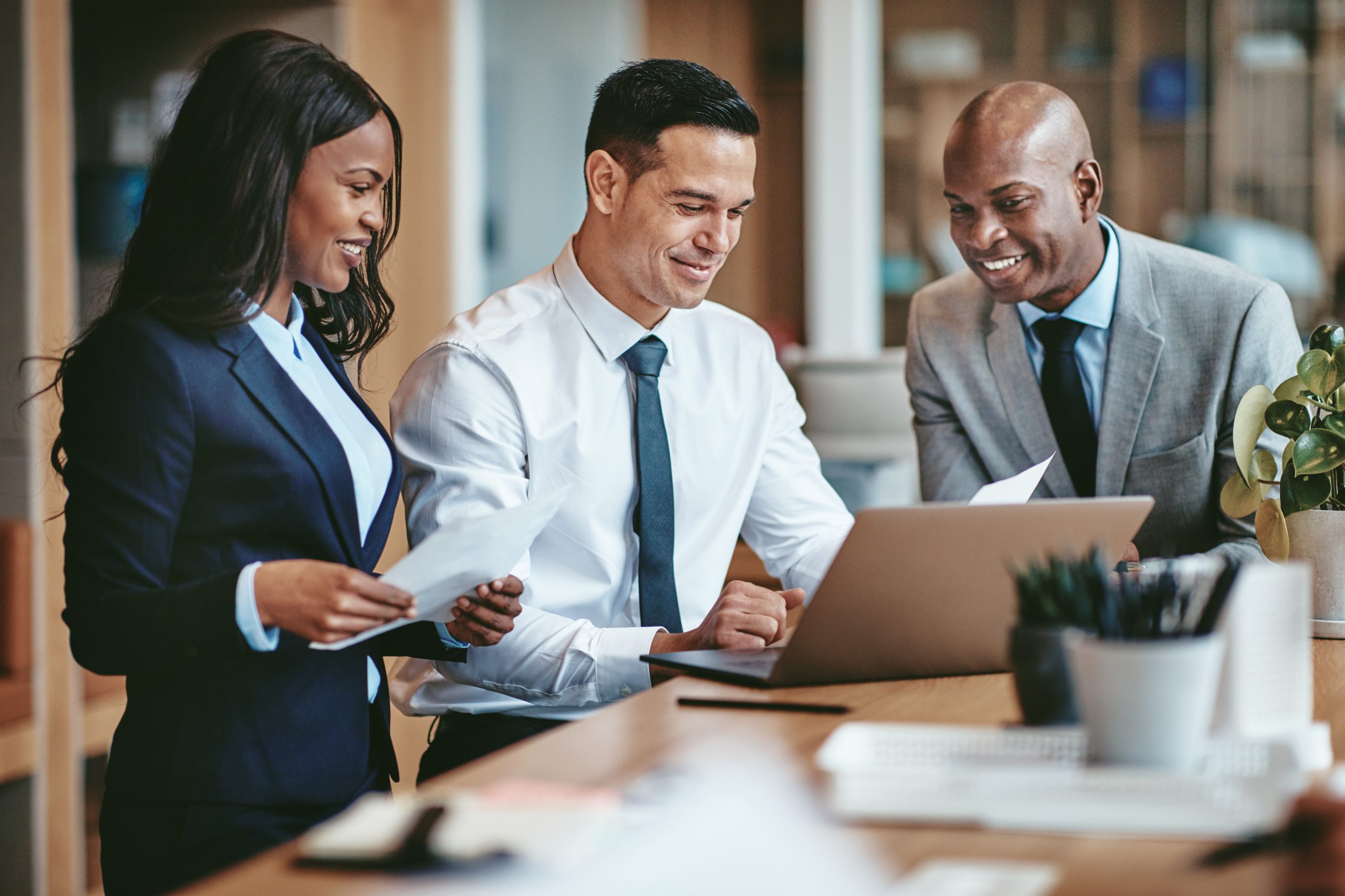 Smiling Group Of Diverse Business People Going Over Paperwork Together