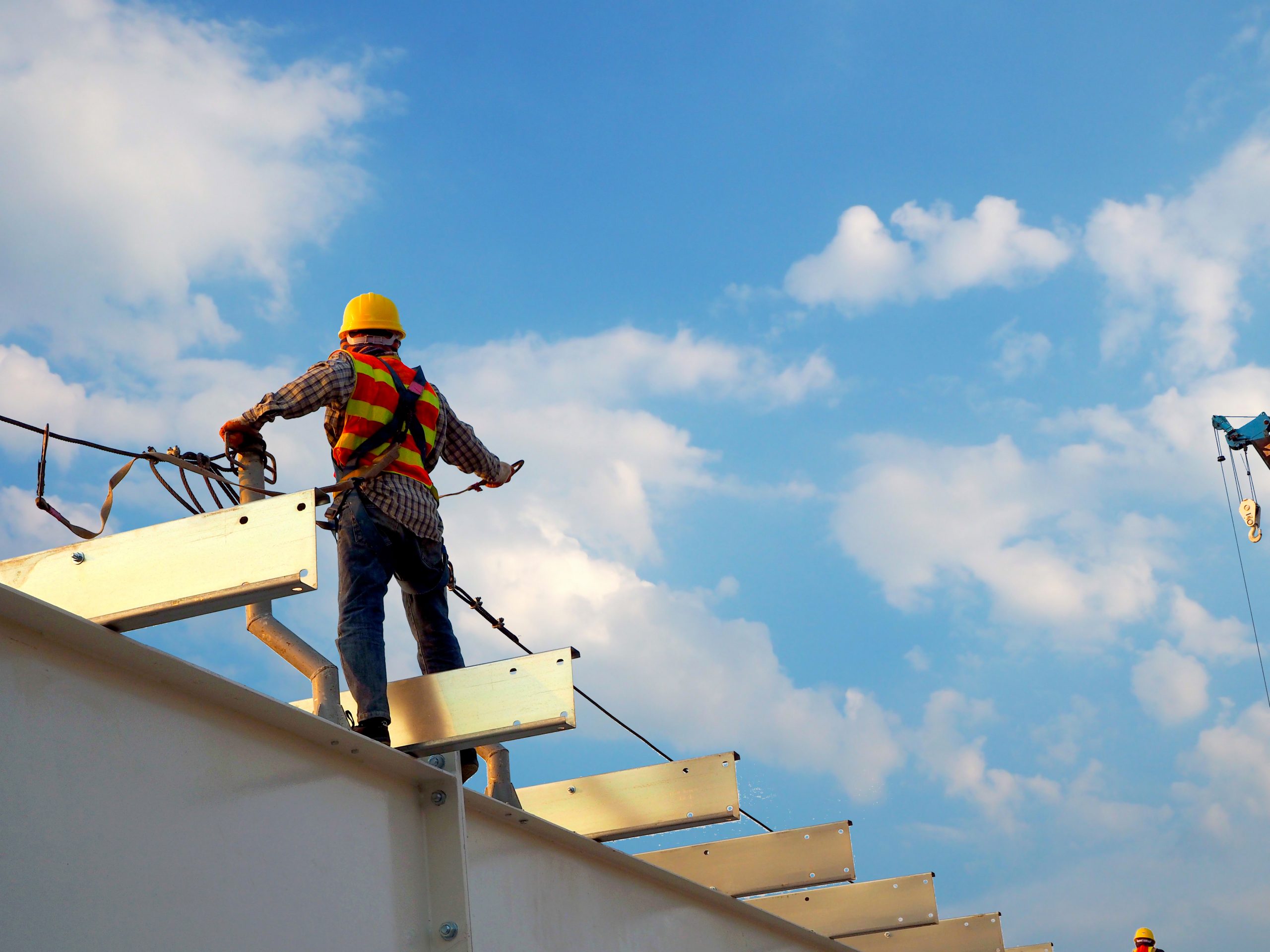 Construction Worker Standing on Metal Beams With Blue Sky In The Background Construction Worker Standing on Metal Beams With Blue Sky In The Background