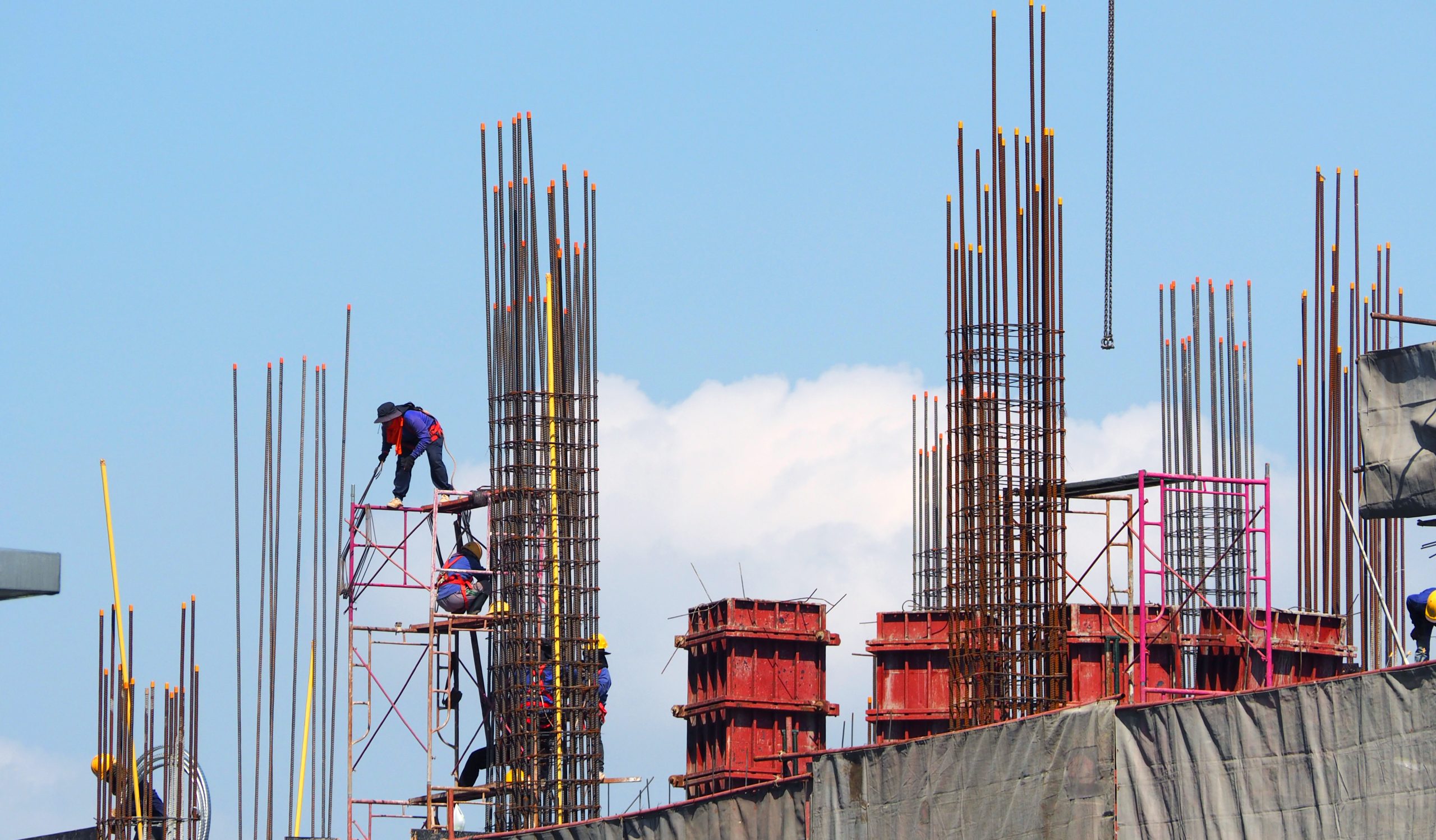 Construction Workers Working On Scaffolding With Metal Trust Rods