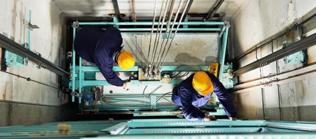 Two Men Working On Top Of An Elevator