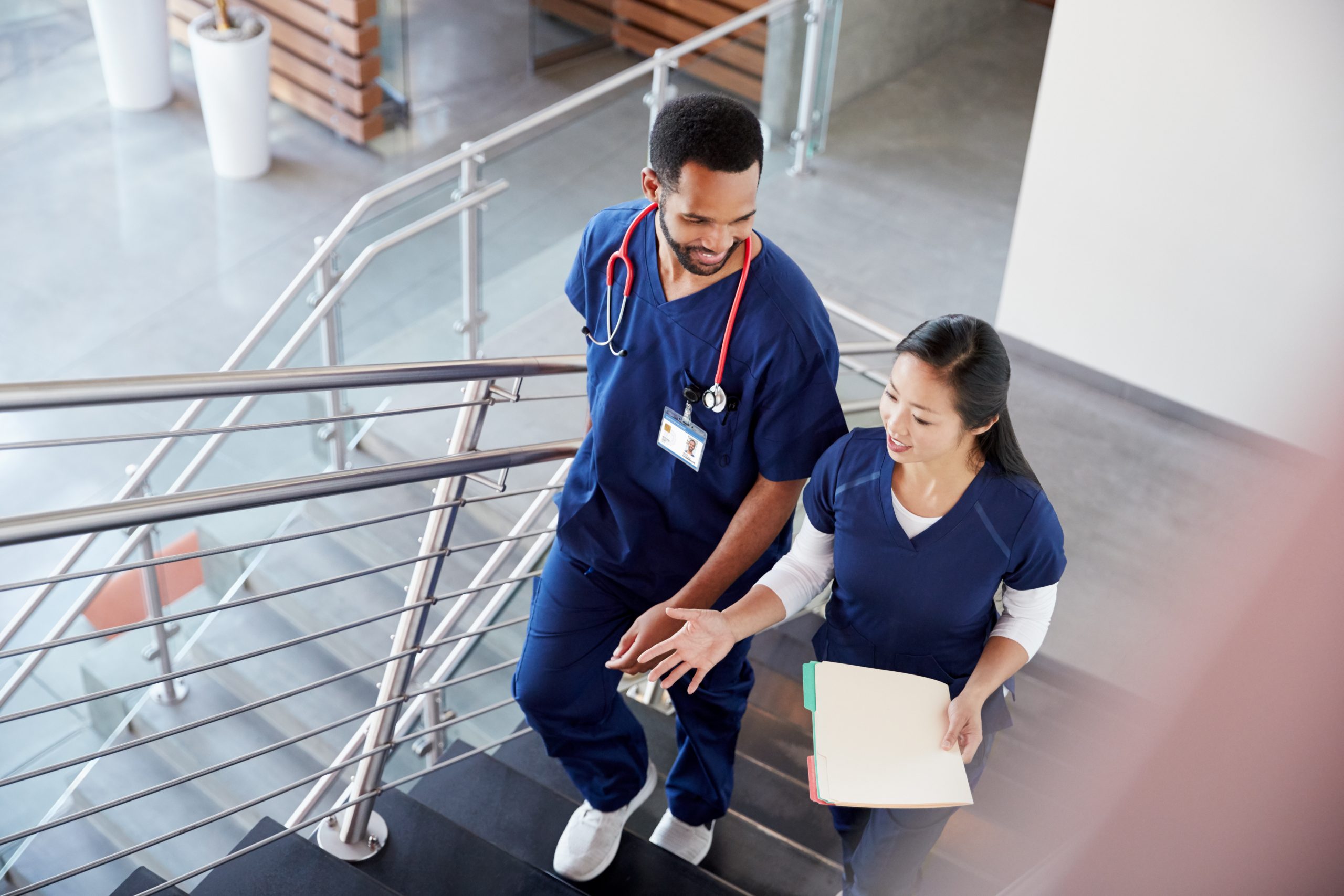 Two,Healthcare,Colleagues,Talking,On,The,Stairs,At,Hospital