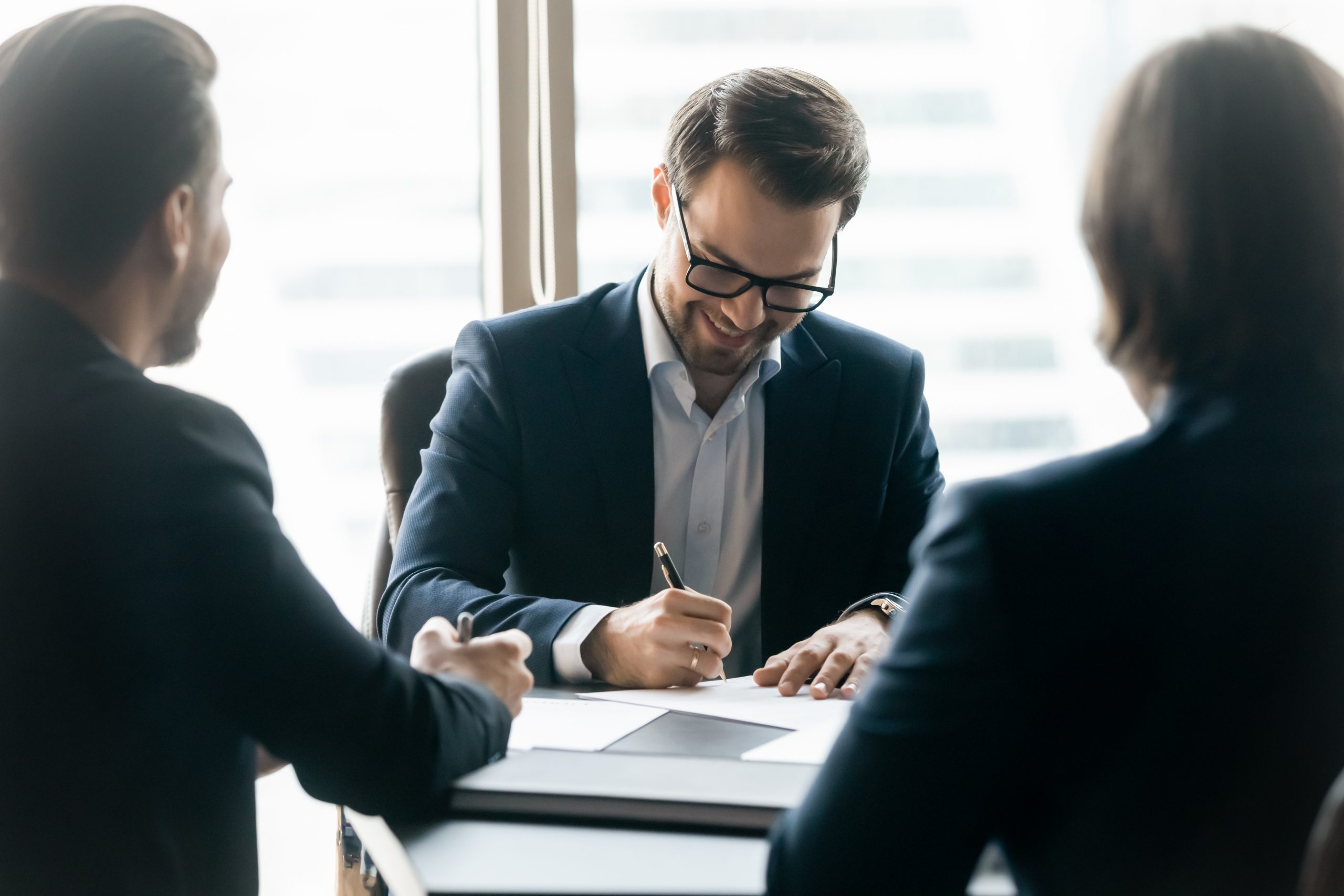 Smiling,Confident,Businessman,Wearing,Glasses,Signing,Contract,At,Group,Negotiations,