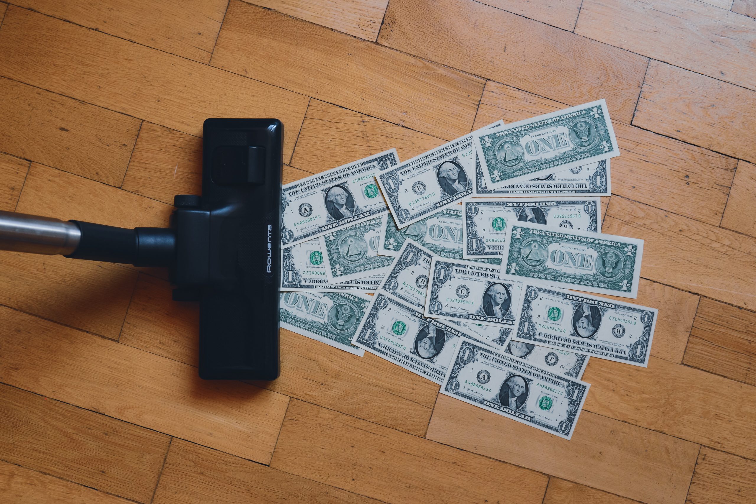 Vacuum Vacuuming Up Several Dollar Bills on Hard Wood Floor