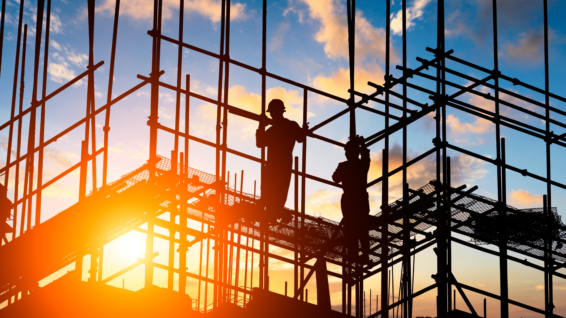 Construction Workers on Scaffolding During Sunset