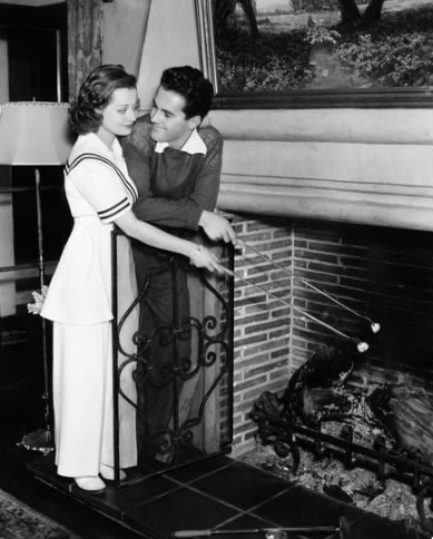 Black and White Photo of Husband and Wife Roasting Marshmallows in Fireplace