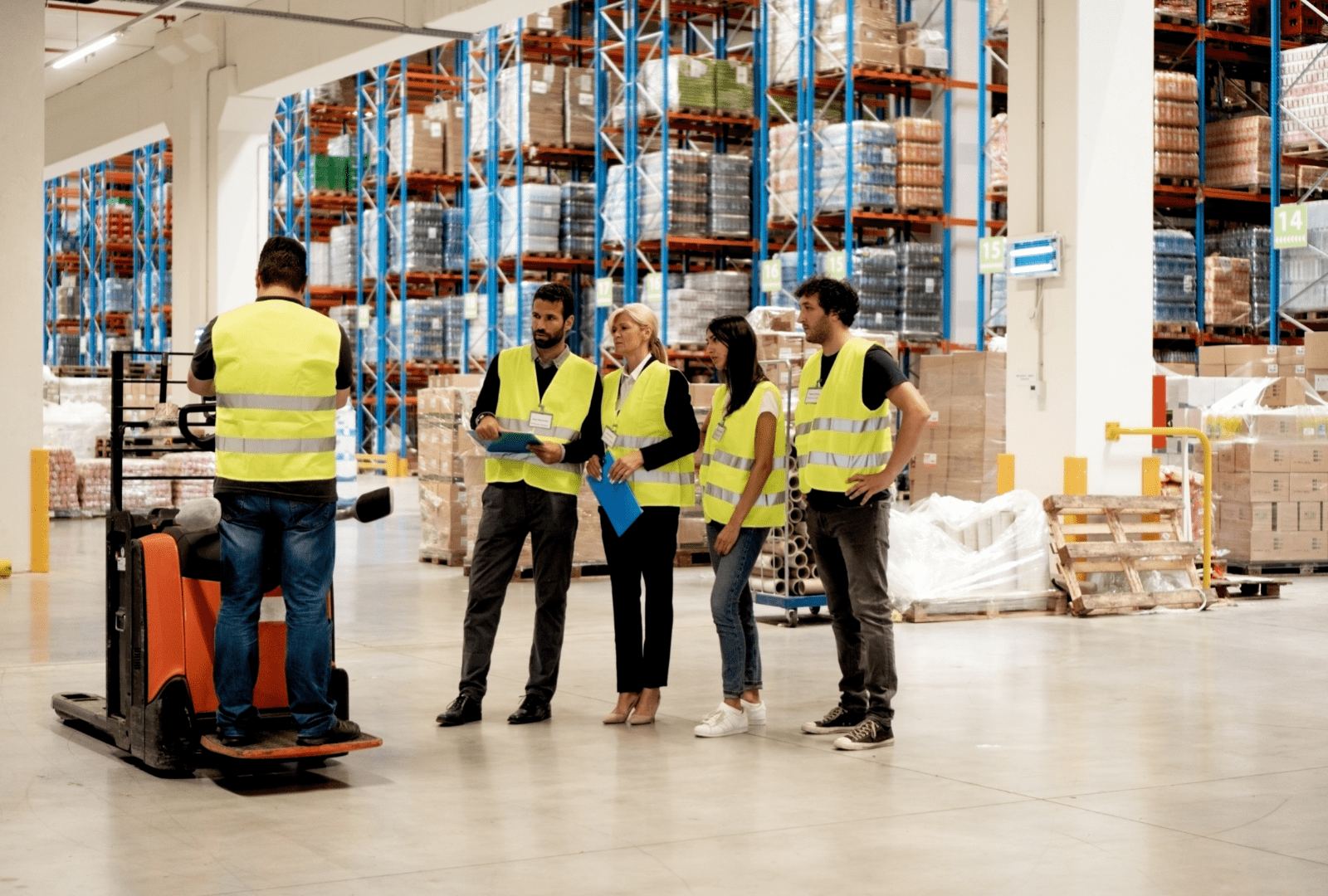 Employees Wearing Safety Vests Undergoing Forklift Training In Warehouse