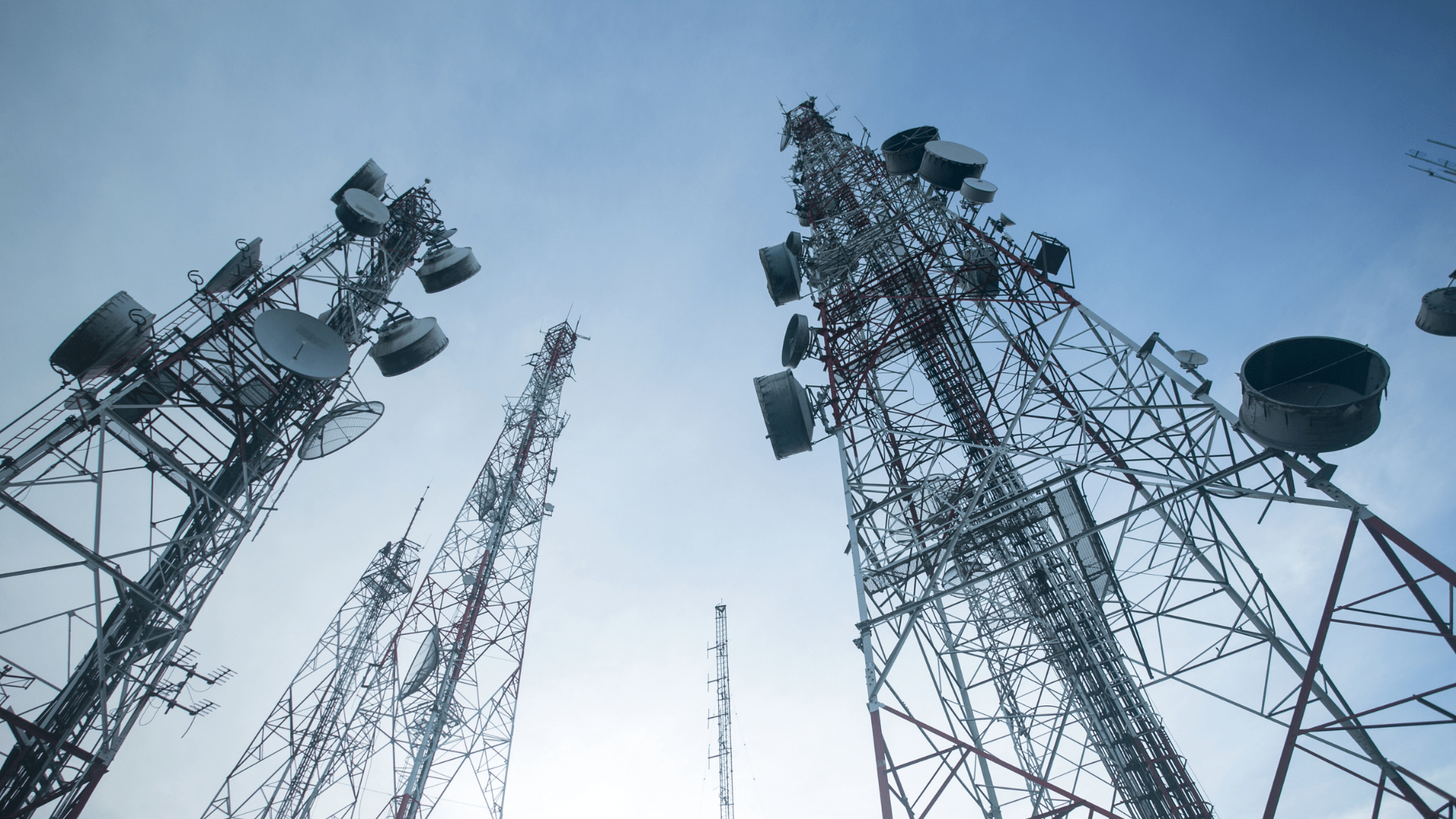 Looking up at Several Telecommunication Towers from the Ground