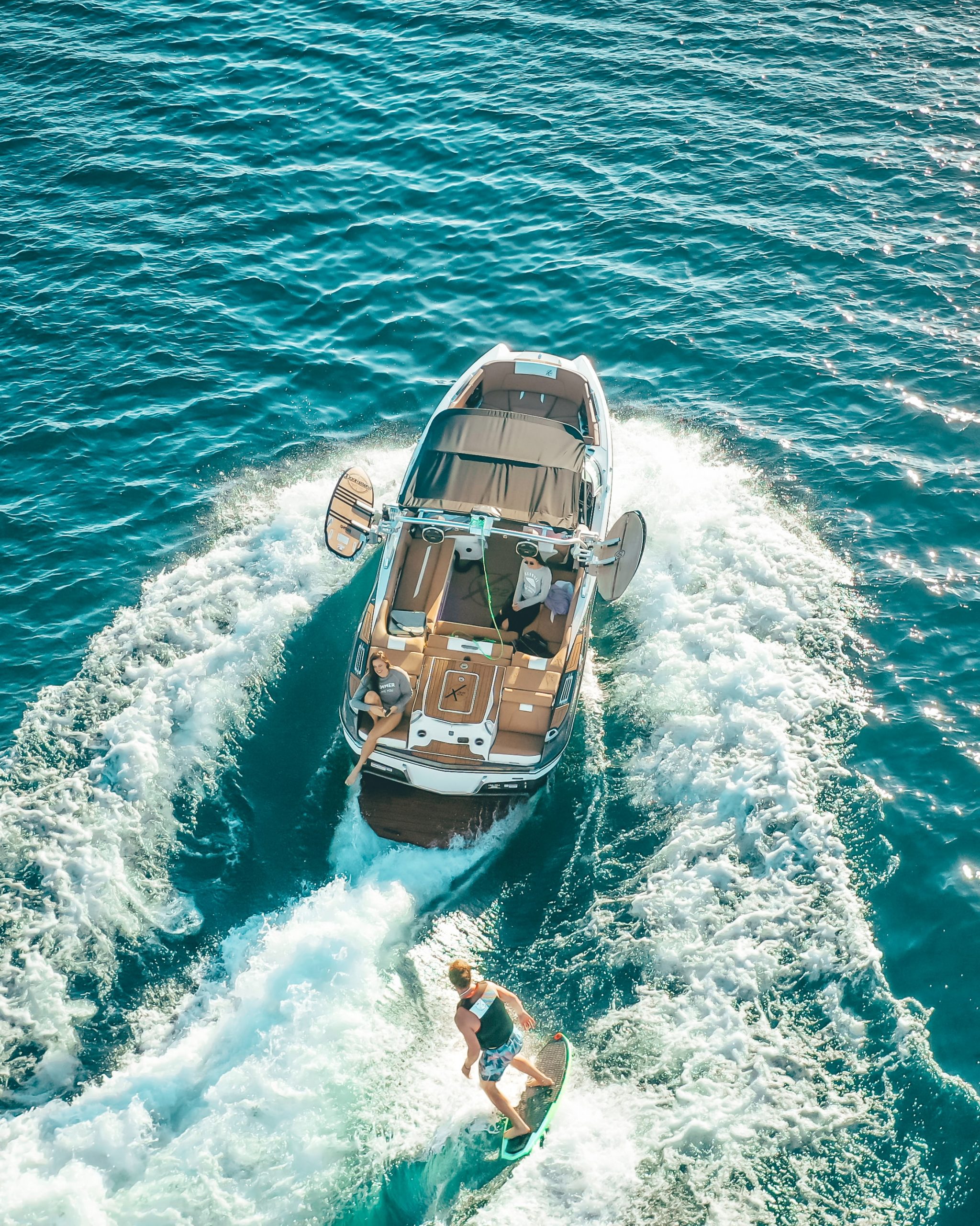 Aerial View of Man Wake Surfing Behind a Boat Aerial View of Man Wake Surfing Behind a Boat