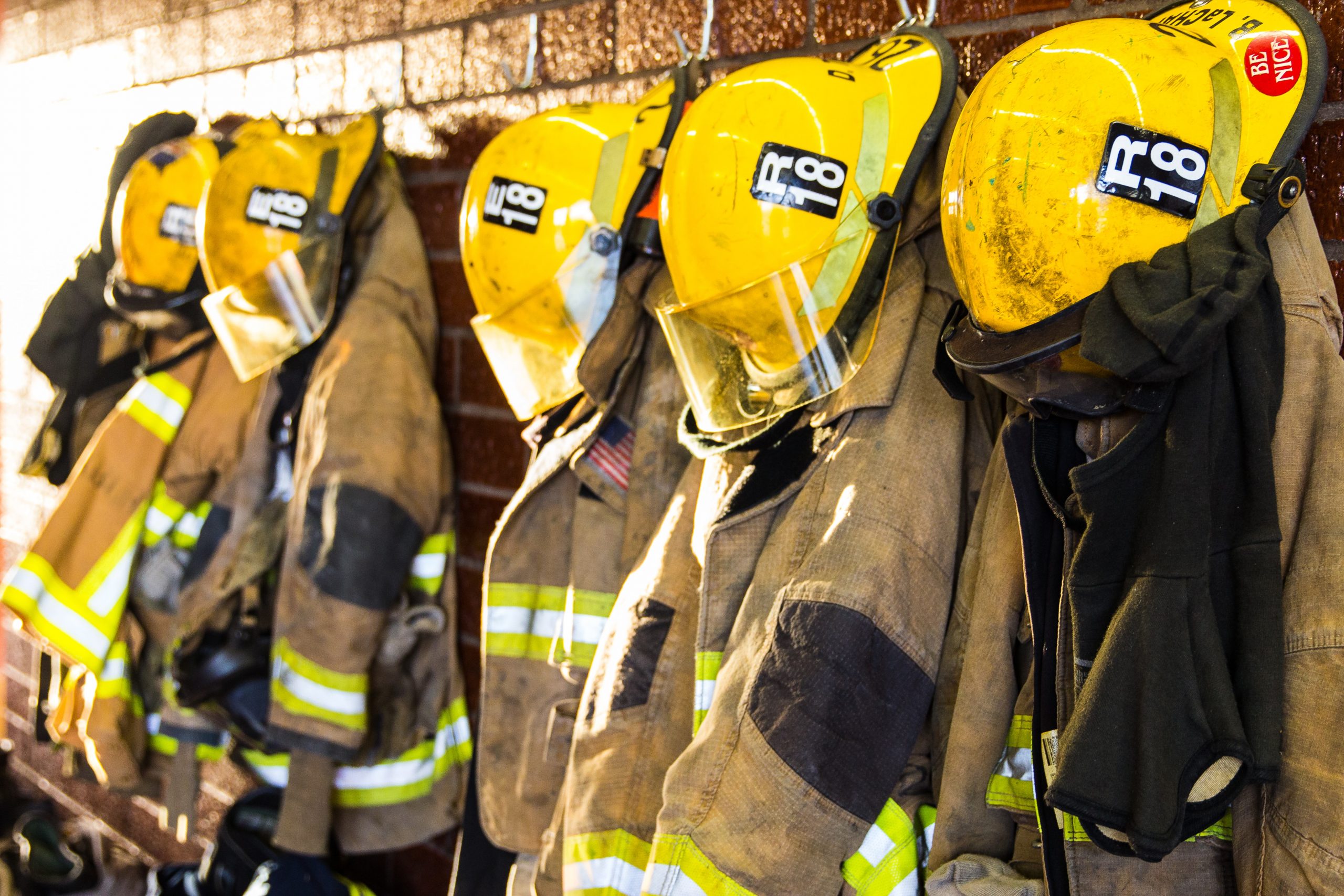 Line of Firefighter Jackets & Helmets Hanging on Wall Line of Firefighter Jackets & Helmets Hanging on Wall