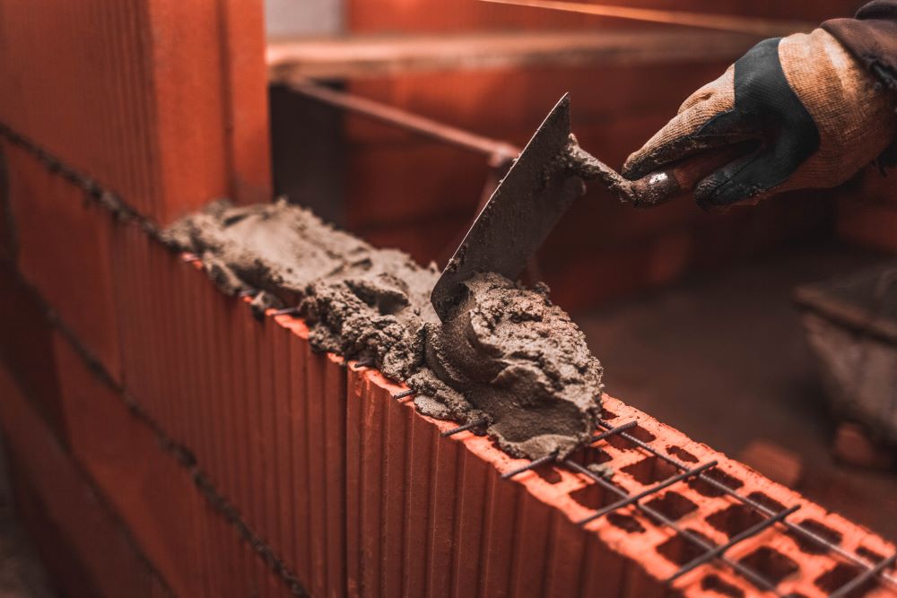 bricklayer-puts-bricks-to-make-a-wall-tower street insurance osha Tower Street Insurance Loss Control OSHA Safe and Sound Week Safety and Health