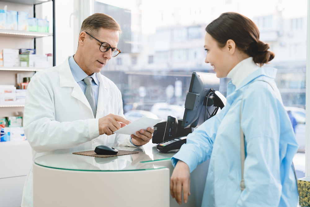 Pharmacist looking at medical prescription selling drugs medications medicines to customer Tower Street Insurance Loss Control OSHA Safe and Sound Week Safety and Health