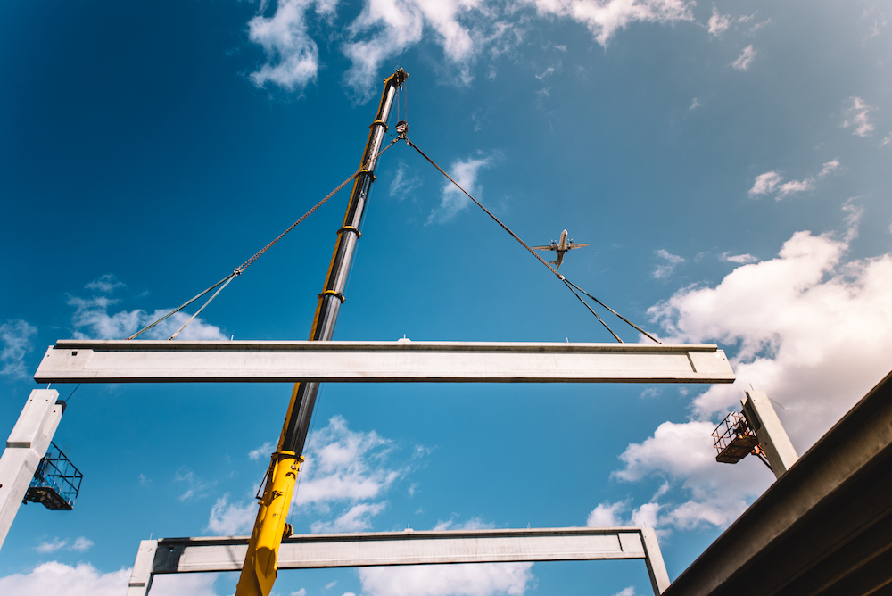 Construction site building assembly - crane lifting a precast concrete cement beam Tower Street Insurance Loss Control OSHA Safe and Sound Week